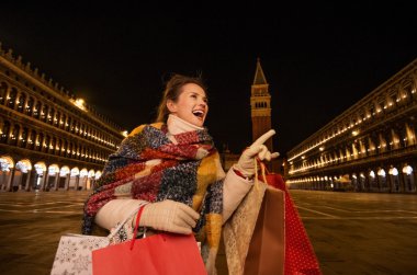 Alışveriş torbaları Venedik iken bir şey üzerinde işaret eden kadınla