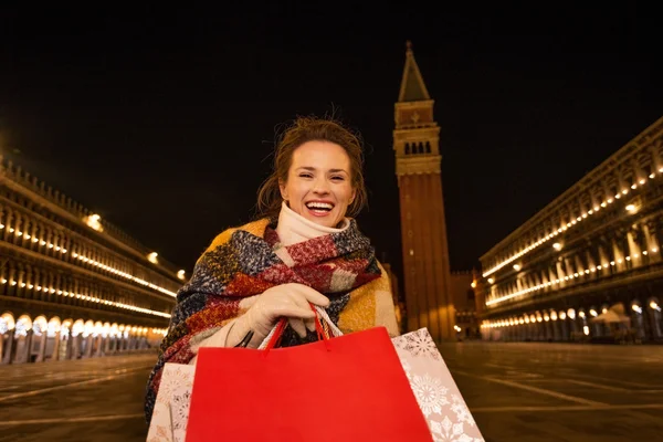 Lachende vrouw met boodschappentassen op Piazza San Marco in avond — Stockfoto