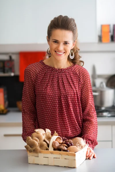 Lachende vrouw in de keuken met mandje met champignons — Stockfoto