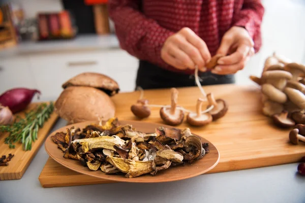 Closeup of mushrooms in a dish with woman stringing mushrooms — Stock Photo, Image