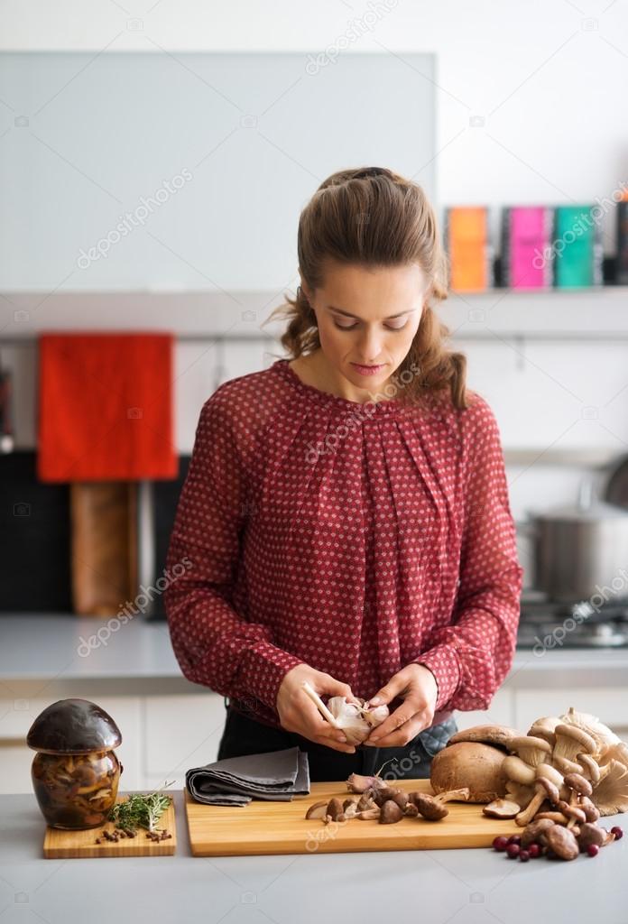 Woman looking down in kitchen preparing garlic and mushrooms