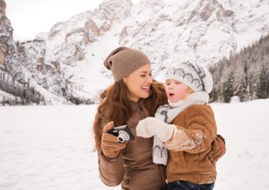 Happy mother and child with photo camera in winter outdoors
