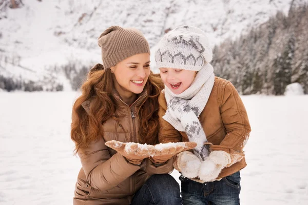 Happy mother and child playing with the snow in winter outdoors — Stock fotografie