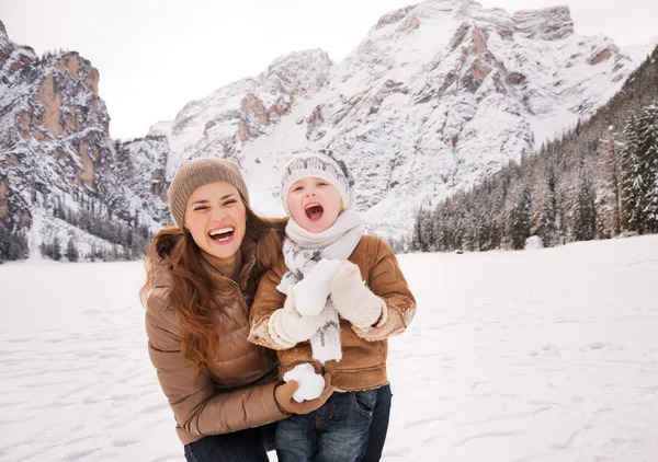 Mother and child playing with snow among snow-capped mountains — Stockfoto