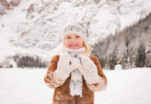 Child showing snowy mittens outdoors among snow-capped mountains — Zdjęcie stockowe