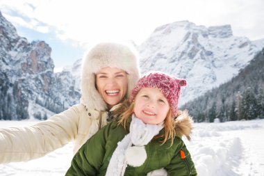 Mother and child taking selfie in front of snowy mountains