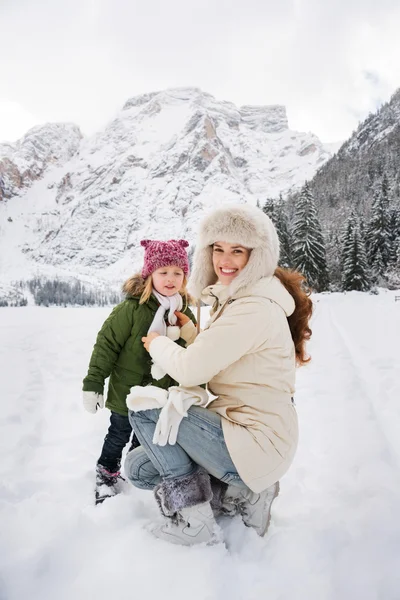 Mother and child playing outdoors in front of snowy mountains — Stockfoto
