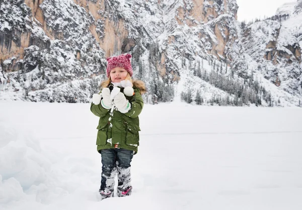 Criança feliz em casaco verde brincando com neve — Fotografia de Stock