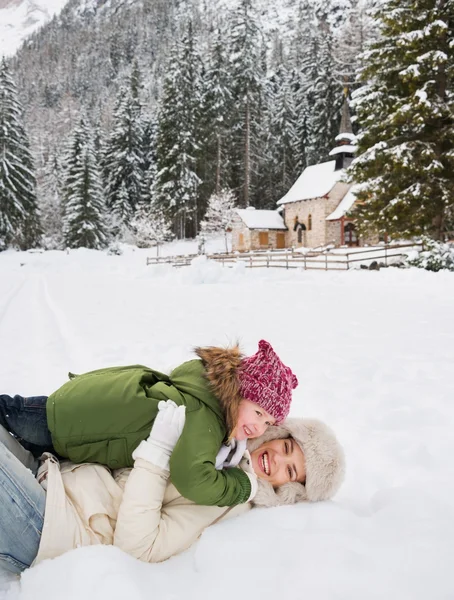 Mother and child playing outdoors in front of snowy mountains — Stok fotoğraf