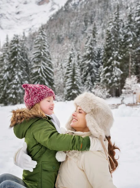 Mother and child playing outdoors in front of snowy mountains — Stok fotoğraf