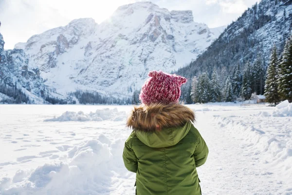 Seen from behind child in green coat playing outdoors. — Zdjęcie stockowe