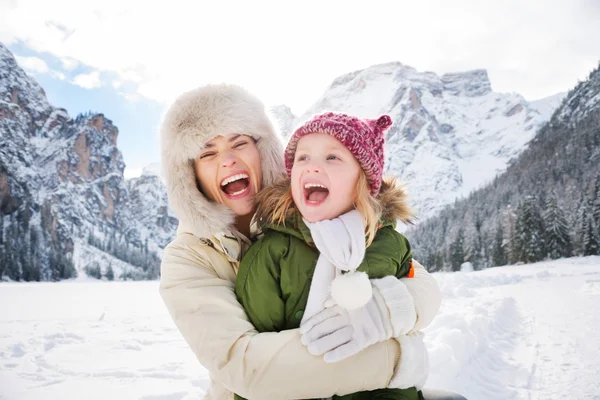 Mother and child hugging outdoors in front of snowy mountains — Stockfoto