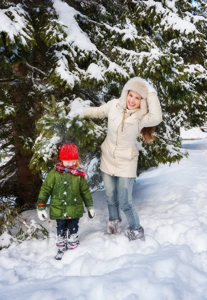 Mère secouant la neige de la branche sur l'enfant tout en se tenant à l'extérieur — Photo