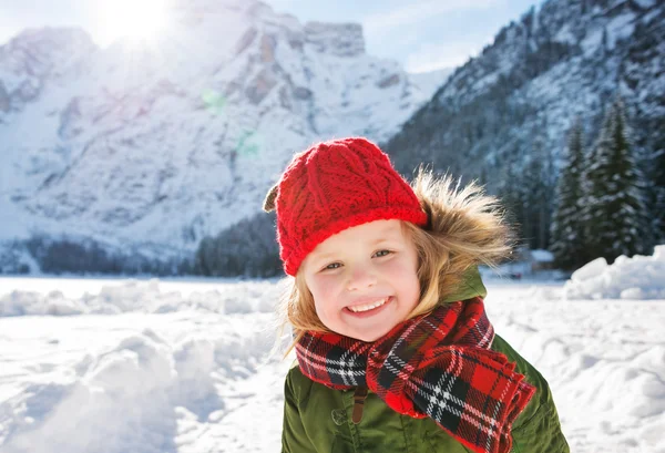 Niño sonriente parado en el frente de las montañas nevadas — Foto de Stock