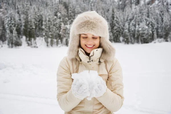 Mujer mirando la nieve en las manos mientras está de pie al aire libre —  Fotos de Stock