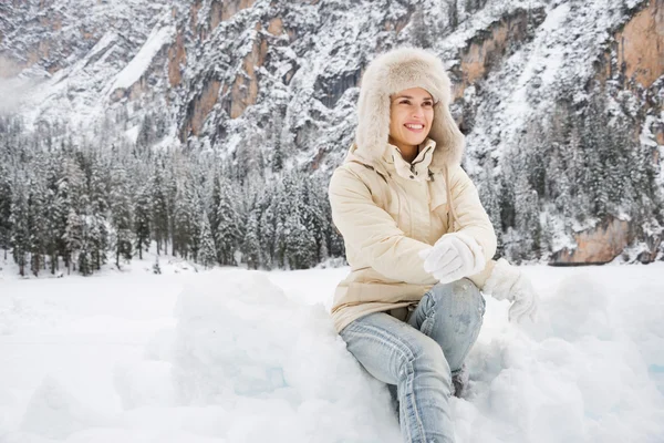 Mulher de casaco branco e chapéu de pele sentado na neve ao ar livre — Fotografia de Stock