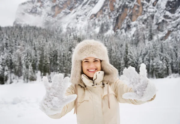 Mulher de casaco e chapéu de pele mostrando luvas cobertas de neve ao ar livre — Fotografia de Stock