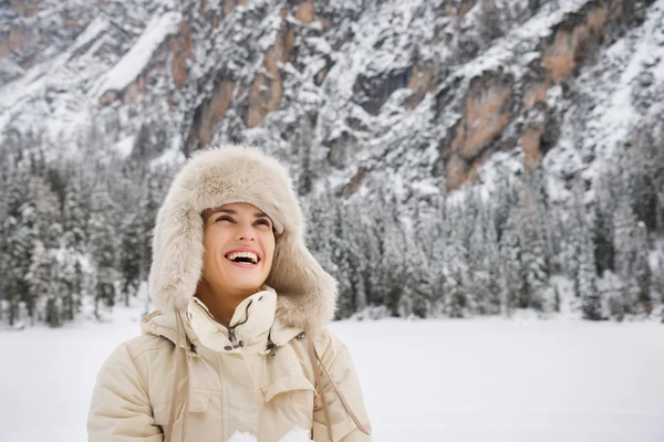 Happy woman in coat and hat looking up while standing outdoors — Stock Photo, Image