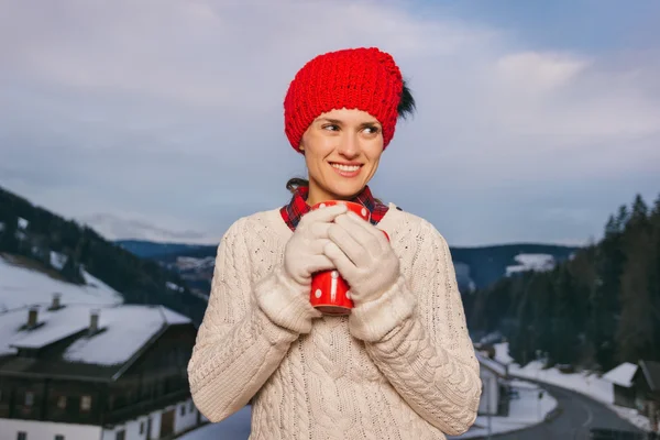 Kobieta z czerwony kubek na balkon z widokiem na góry w wieczór — Zdjęcie stockowe