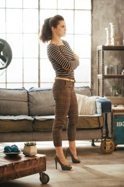 Çatı katında kalan çapraz kolları olan zengin kahverengi saçlı kadın