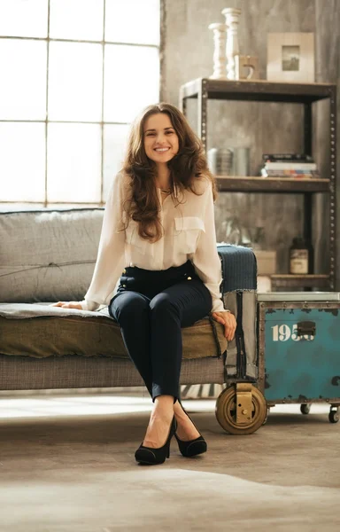 Mosolyogva Brunet nő elegáns ruhát ül a padláson szoba — Stock Fotó