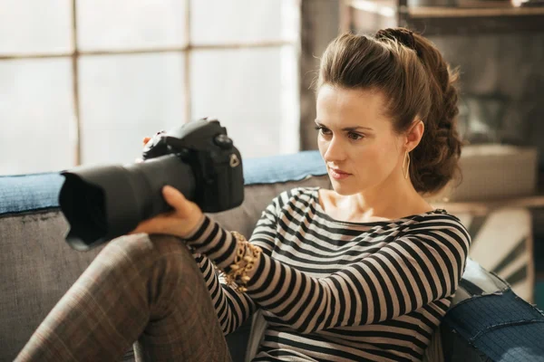 Young brunet woman is sitting and holding dslr camera — 图库照片