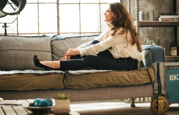 Sorrindo relaxado jovem mulher está relaxando no sofá — Fotografia de Stock