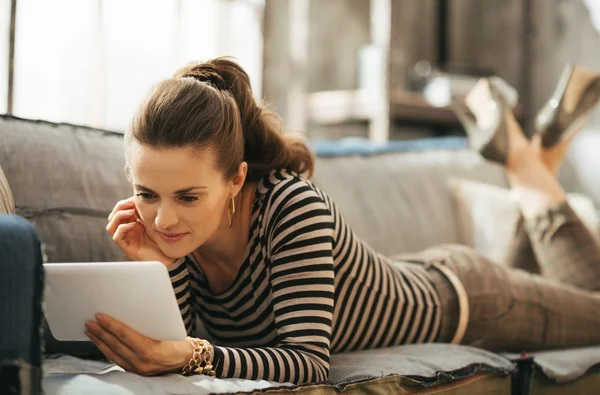 Concentrated female is laying down and working on tablet — Stock Photo, Image