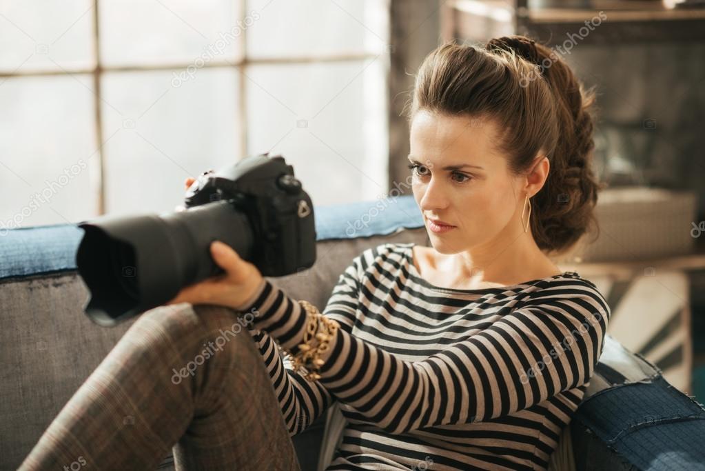Young brunet woman is sitting and holding dslr camera