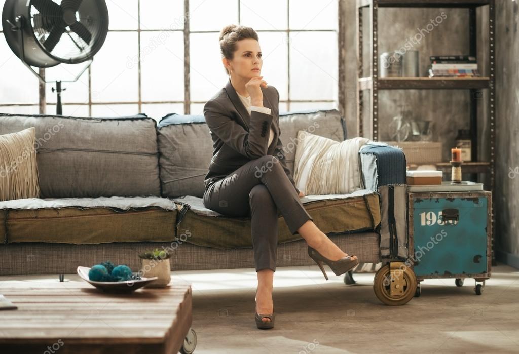 Elegant brunet business woman is sitting on couch in loft