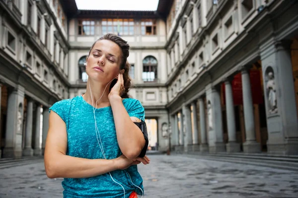 Retrato de mujer joven y relajada en ropa deportiva escuchando mp3 — Foto de Stock