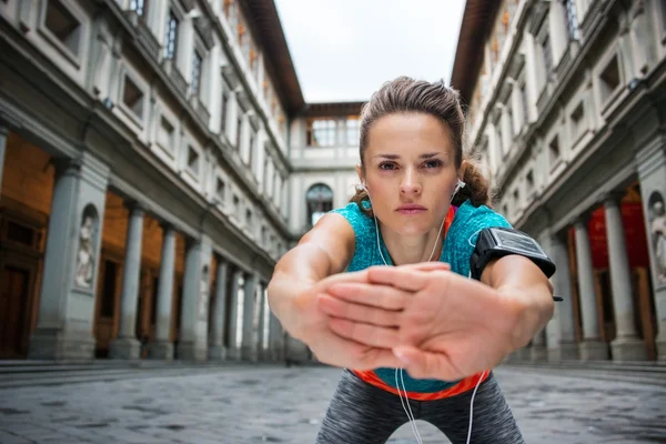 Sportswoman with headset is stretching next to Uffizi gallery — ストック写真