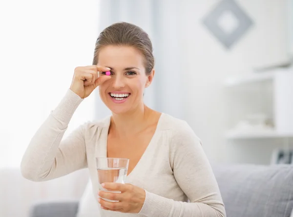 Retrato de mujer joven feliz con píldora y vaso de agua —  Fotos de Stock