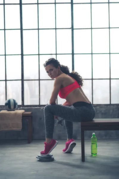 Fitness woman with dumbbell sitting in loft gym — Stock Photo, Image