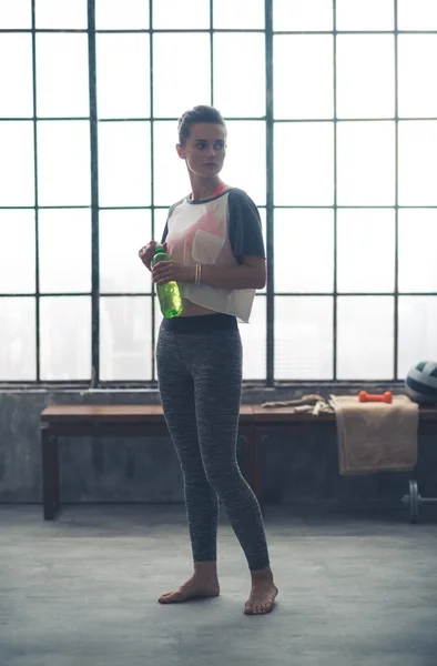 Fitness woman with bottle of water in loft gym — Stock Photo, Image