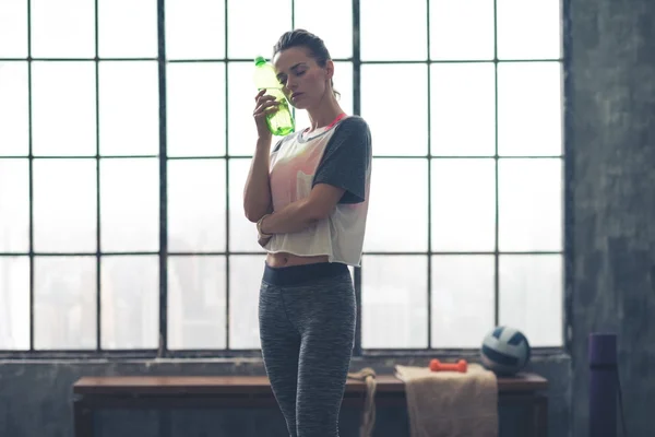 Kobieta w poddaszu siłowni chłodzenia po treningu za pomocą butelki wody — Zdjęcie stockowe