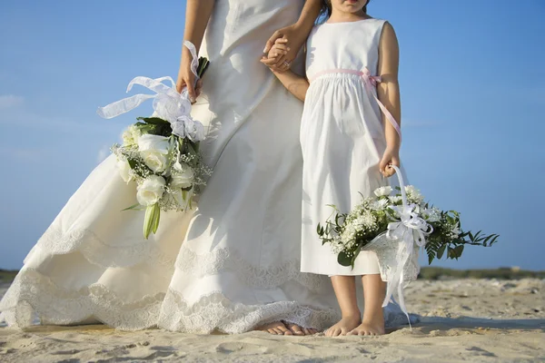 新娘和海滩上的花姑娘 图库照片