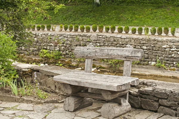 Panca in legno sulla riva del fiume lapidata — Foto Stock