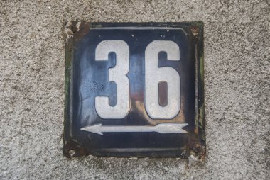 Yıpranmış kare metal plaka numarası 36 olan sokak adresi.