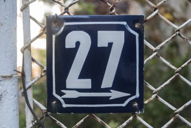 Yıpranmış, köhne, metal plakalı, 27 numaralı sokak adresi.