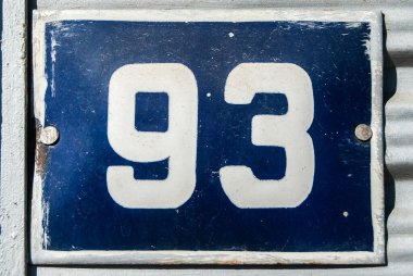 Yıpranmış, köhne, metal kaplamalı, üzerinde 93 numara olan sokak adresi.