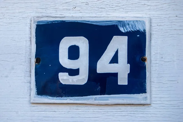 Weathered grunge square metal enameled plate of number of street address with number 94