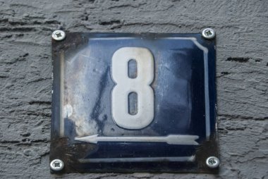 Yıpranmış, köhne, metal plakalı, üzerinde 8 numara olan sokak adresi.