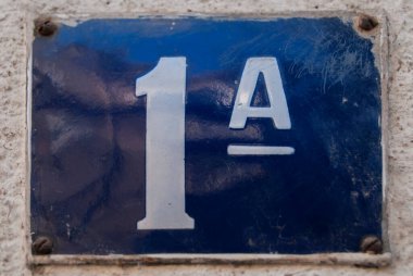 Yıpranmış 1 numaralı sokak adresinin plakası işlemeli eski bir kare metal.