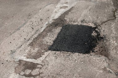 Çatlak asfalt yol yüzeyi ve yakın çekim yaması