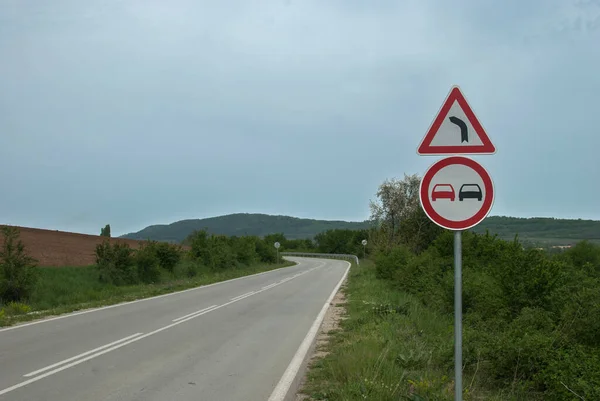 カントリーロードは 道路カーブの注意交通標識とオーバーテイク禁止サインアップで曲げ — ストック写真