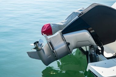 Dış motorun ve pervanenin yakın çekim detayı. Rıhtımdaki deniz teknesinde, suyun üstünde.