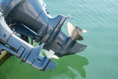 Dış motorun ve pervanenin yakın çekim detayı. Rıhtımdaki deniz teknesinde, suyun üstünde.