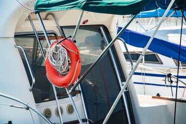 Limandaki bir teknede asılı duran turuncu halkalar, halatlar ve çamurluklar.