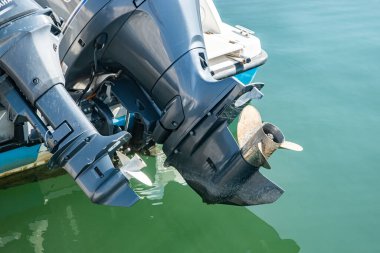 Dış motorun ve pervanenin yakın çekim detayı. Rıhtımdaki deniz teknesinde, suyun üstünde.